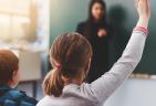 Child in classroom raising hand to ask a question