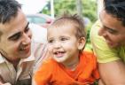 A smiling toddler with two men