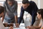 Four people at a conference table sharing notes